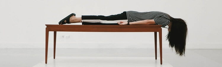 Frau liegt auf Tisch und Haare hängen herunter